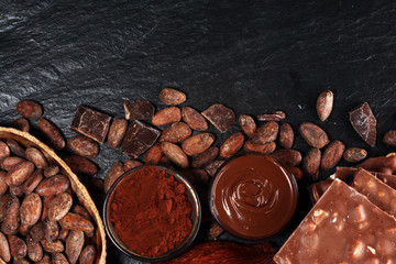 Melting chocolate or melted chocolate with a chocolate swirl and stack, chips and powder on black