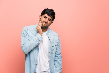 Young man over pink wall with toothache