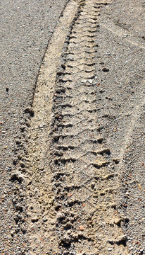 a tyre tread of a vehicle wheel on the brown sand off road. Vertical photo