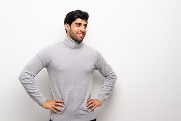 Fototapeta premium Young man over isolated white wall posing with arms at hip and smiling