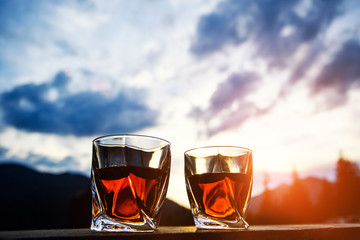 whiskey at sunset dramatic sky on mountain landscape background