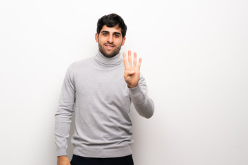 Young man over isolated white wall happy and counting four with fingers