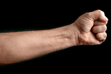 Fist isolated on black background. A strong man raised his fist on a black background, power, protest, fist ready for battle.