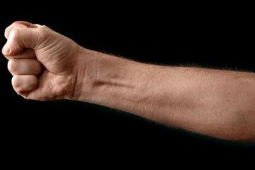 Fist isolated on black background. A strong man raised his fist on a black background, power,...