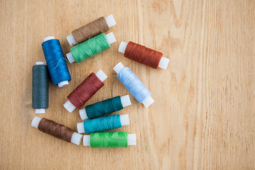 Fototapeta na wymiar Multicolored sewing threads on the wood ground