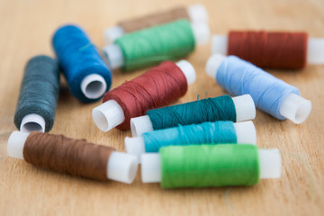 Fototapeta na wymiar Multicolored sewing threads on the wood ground