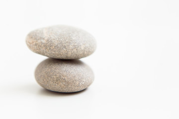 Fototapeta na wymiar Two pebbles against each other on the white ground