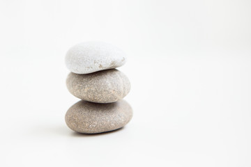 Fototapeta na wymiar Three pebbles against each other on the white ground