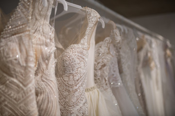 Wedding dresses hang on hangers. Factory of wedding dresses.