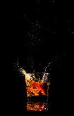 whiskey with splash on black background, brandy in a glass