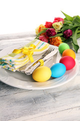 Festive table setting for Easter with fork, knife and tulip on table