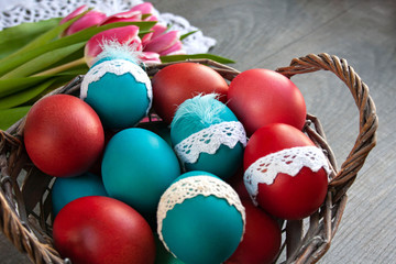 A basket full of colorful Easter eggs, in the background pink tulips