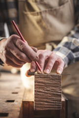 Fototapeta na wymiar Handwerker markiert ein Stück Holz mit dem Bleistift