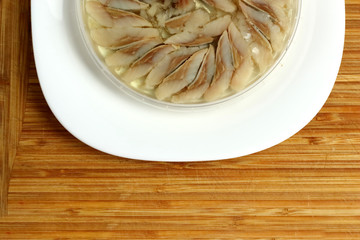 canned russian fish pieces of herring in oil in a jar on a white plate and wooden board  with bread