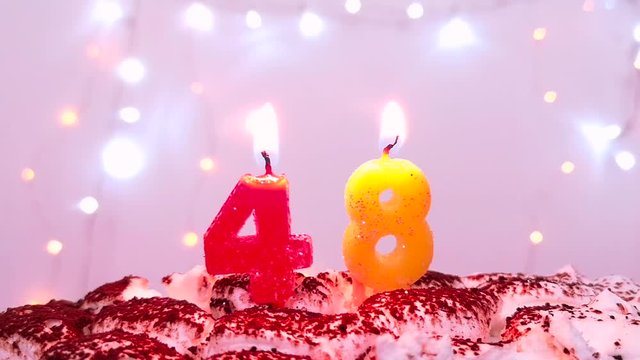 Burning birthday candle on a birthday cake. Number 48, blow out at the end. Color blurred background. 