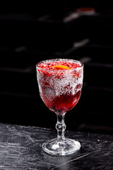 Christmas mulled wine. Red mulled wine in a beautiful faceted glass with cranberries and orange slice. Dark background. close-up. space