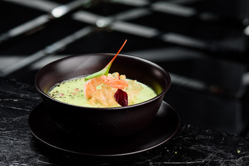 Green Cream Soup with Shrimp . Thai food Shrimp green curry in a dark plate on a black background 