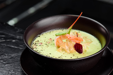 Green Cream Soup with Shrimp . Thai food Shrimp green curry in a dark plate on a black background 