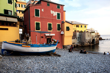 Obraz premium old boat on the sea on the background of old Italian houses in the city of Genoa on a warm summer evening