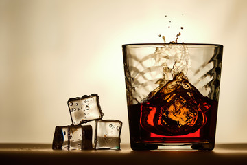 Ice cubes next to a glass of whiskey