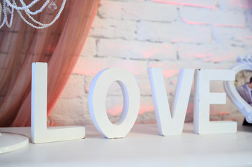 The word "love" in big white separate wooden letters on a white table in a banquet room