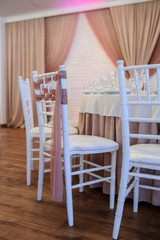 Fototapeta na wymiar close up photo of white chairs decorated with brown textil in a banquet hall in white and brown colors decorated for the event