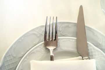 close up photo of knife and fork in a folded napkin on two plate