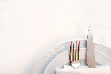 close up photo of knife and fork in a folded napkin on two plate
