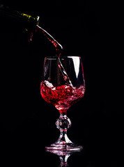 Naklejka na ściany i meble Red wine pouring into wine glass