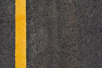 Fototapeta premium Yellow line on black asphalt road background with copy space