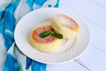 Cheesecake and mint. Cottage cheese pancakes or curd fritters decorated powdered sugar in plate close view. Healthy and diet breakfast.