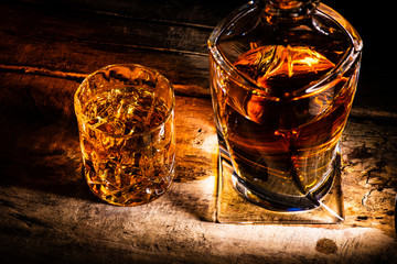 whiskey with ice cubes on wooden background