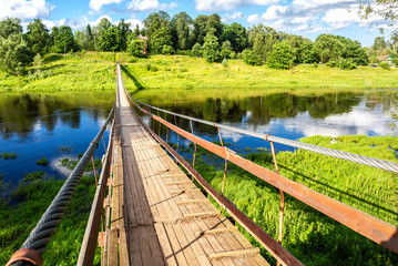 Fototapeta premium Suspension bridge across the Msta river in Borovichi, Russia