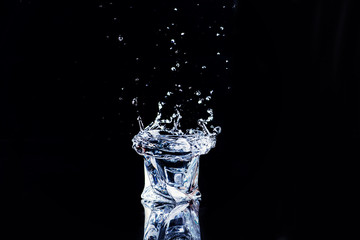 water in a glass with splash and cubes of ice on black background