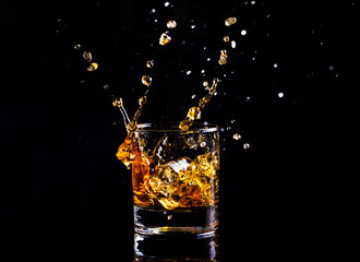 whiskey with splash on black background, brandy in a glass