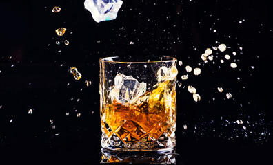 whiskey with splash on black background, brandy in a glass