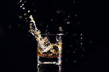whiskey with splash on black background, brandy in a glass