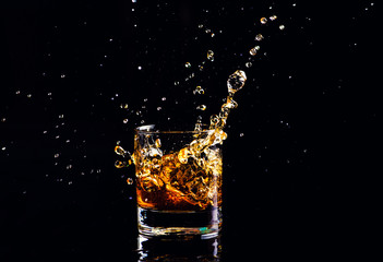 whiskey with splash on black background, brandy in a glass