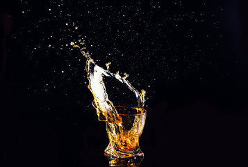 whiskey with splash on black background, brandy in a glass