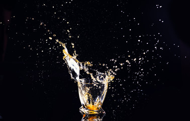 whiskey with splash on black background, brandy in a glass