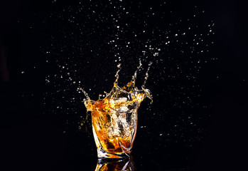 whiskey with splash on black background, brandy in a glass