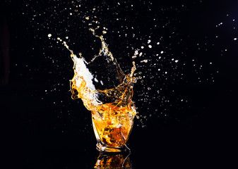 whiskey with splash on black background, brandy in a glass