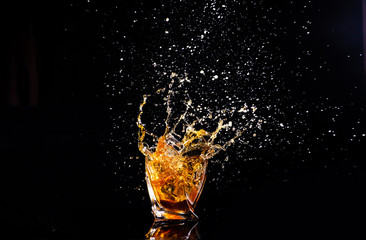whiskey with splash on black background, brandy in a glass