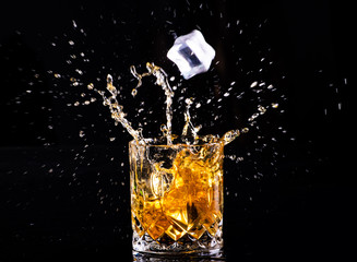 whiskey with splash on black background, brandy in a glass