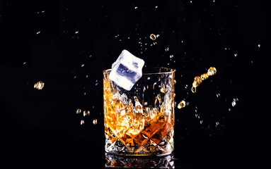 whiskey with splash on black background, brandy in a glass