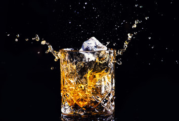 whiskey with splash on black background, brandy in a glass