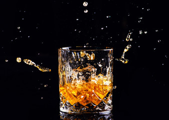 whiskey with splash on black background, brandy in a glass