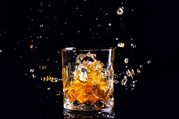 whiskey with splash on black background, brandy in a glass