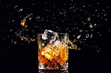 whiskey with splash on black background, brandy in a glass