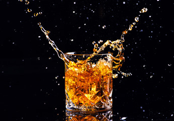 whiskey with splash on black background, brandy in a glass